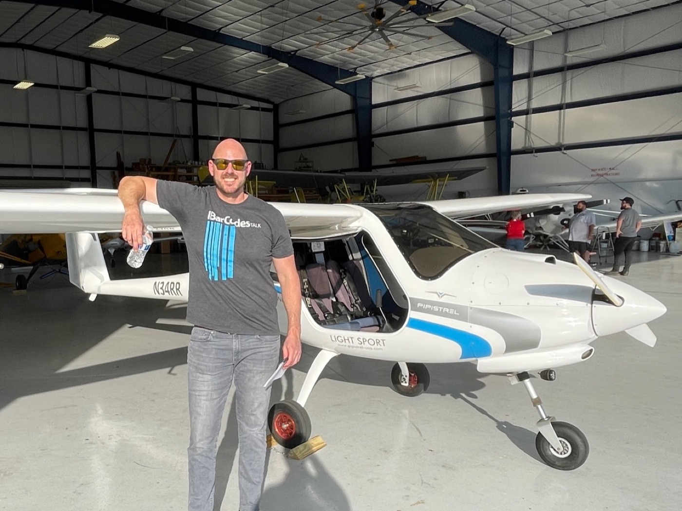Jonathan leaning on a Pipistrel Alpha Trainer in a hangar